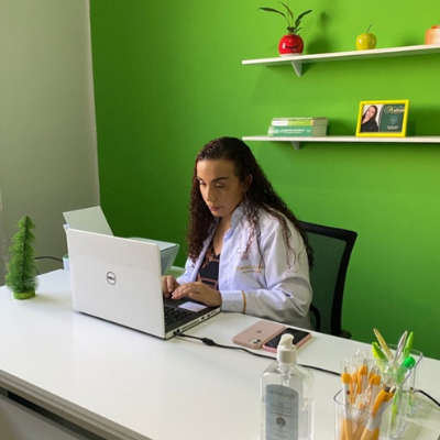 Mulher em consultório nutricional com notebook branco na mesa